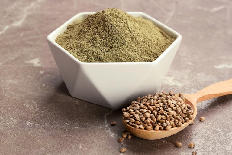 a spoon full of hemp seeds, and a bowl of protein powder